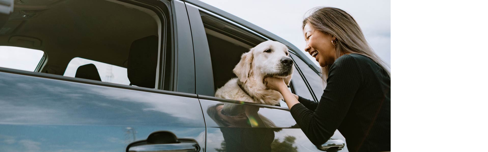 Woman petting the dog in her car through the window