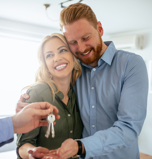 Man and woman being handed keys to new home.